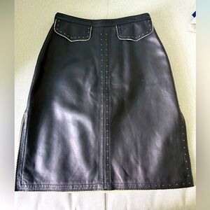 Black leather skirt with side slits, accent pockets and white stitching.Pristine
